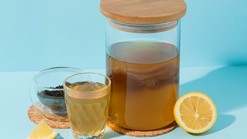 Стеклянная банка с чаем и деревянной крышкой, стакан с чаем и лимон